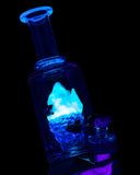 Image of Empire Glassworks Avenge the Arctic UV Glass Attachment for Puffco Peak in the dark and middle design piece is glowing.